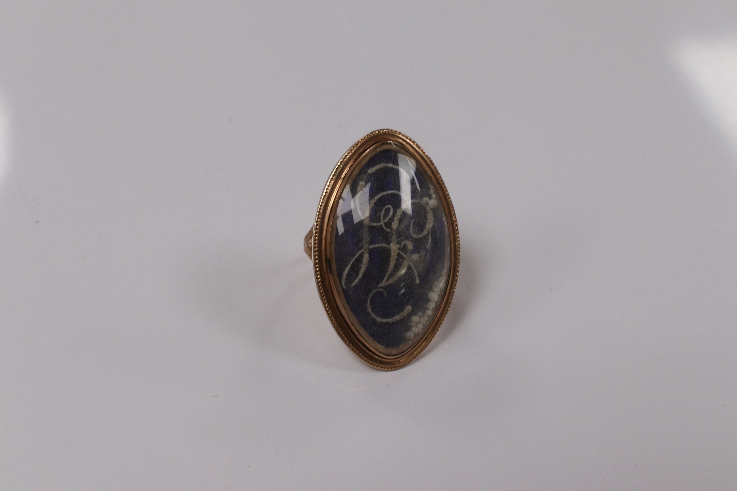 A George III yellow metal, enamel and simulated seed pearl set initialled oval mourning ring, with engraved inscription, 'Isaac Sparks ob. 17th Jan, 1788 ae. 60' size G/H, gross weight 7.6 grams. Condition - poor